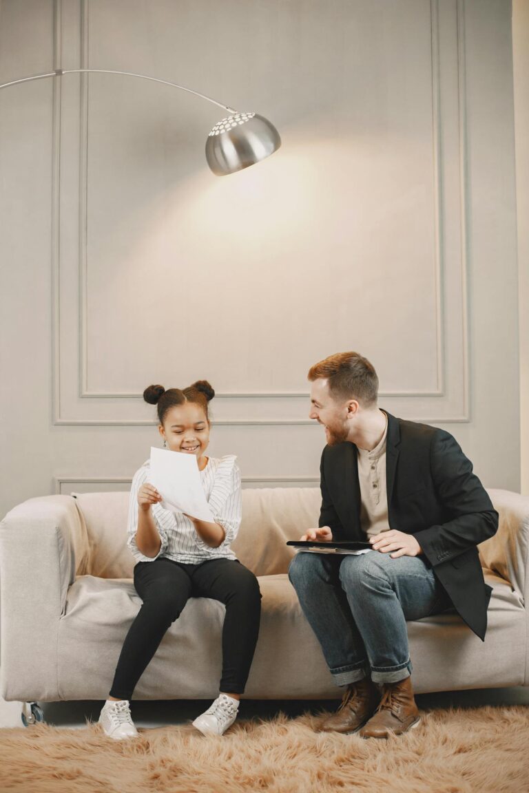 Therapist and child sharing a light moment during a counseling session on a cozy sofa.